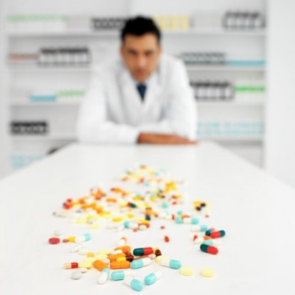 Front view portrait of pharmacist standing in front of table with tablets
