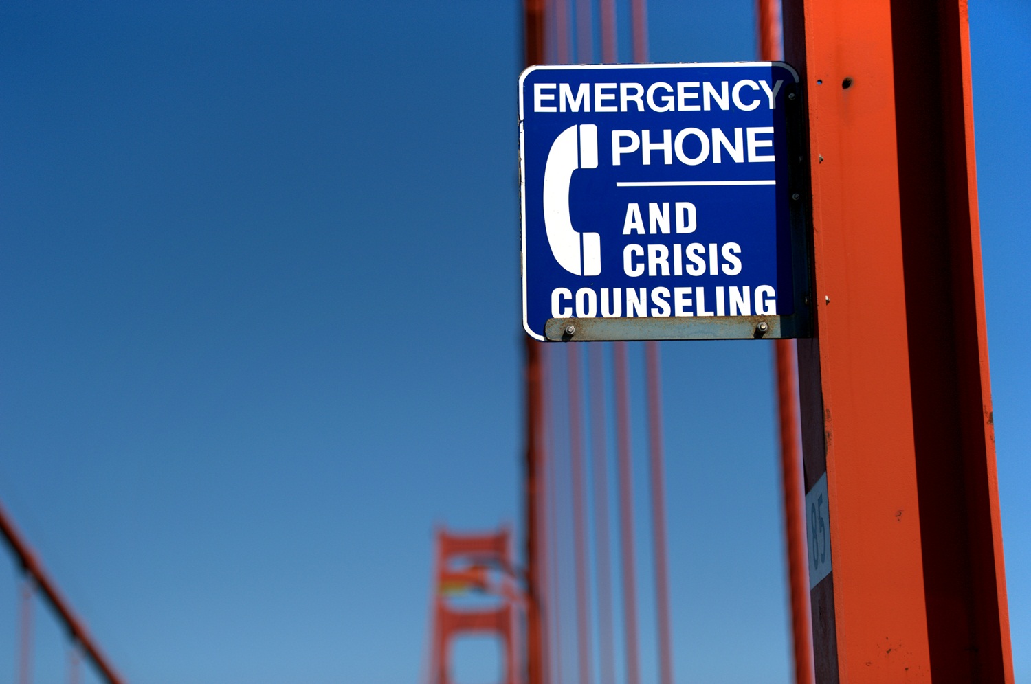 Suicide prevention sign on the east sidewalk of the Golden Gate Bridge, San Francisco, California. The sign reads "Emergency phone and crisis counseling."