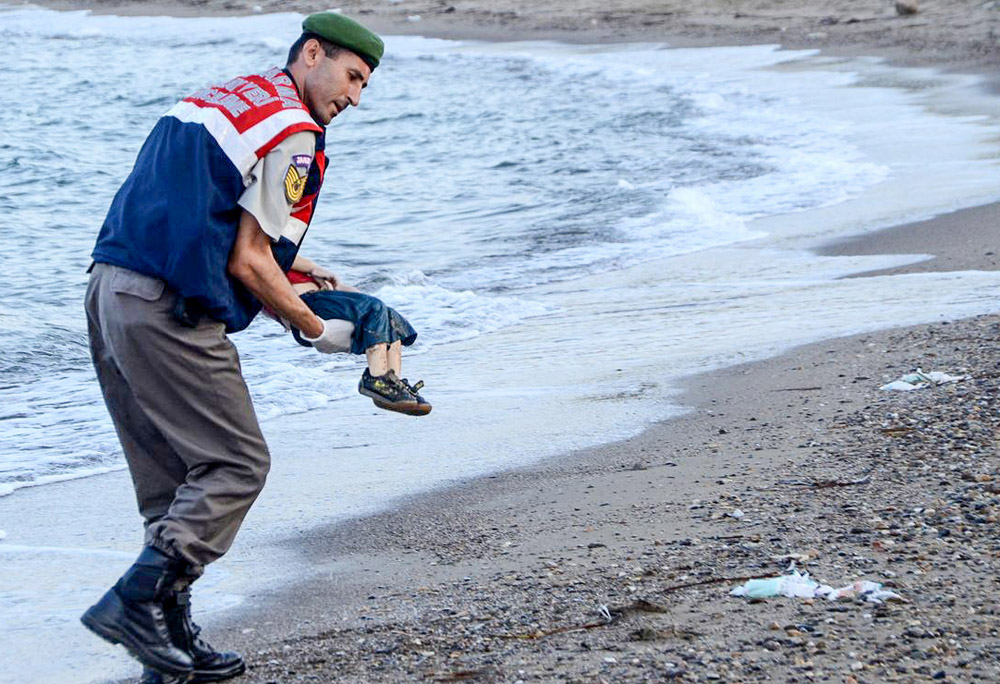 A Turkish police officer carries a migrant child's dead body off the shores in Bodrum, southern Turkey, on Sept. 2 after a boat carrying refugees sank while reaching the Greek island of Kos. (AFP/Getty Images)