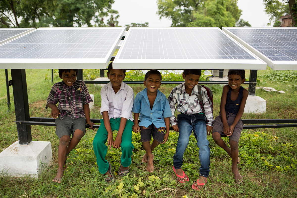 Children sit under solar panels at Bishunpur Tolla, Dharnai village. A solar-powered micro-grid is now supplying electricity to the village.